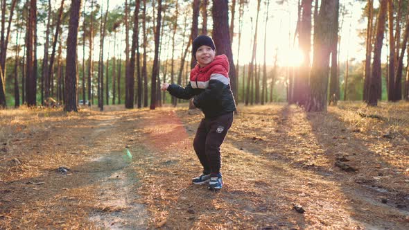 Cheerful Little Boy Dance on the Pine Forest at Sunset