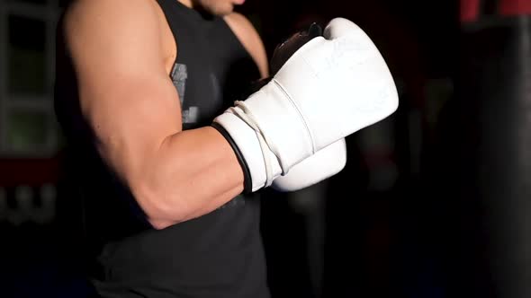 Muscular Man in Black Clothes Puts on Leather White Boxing Gloves on His Hands Before a Competition