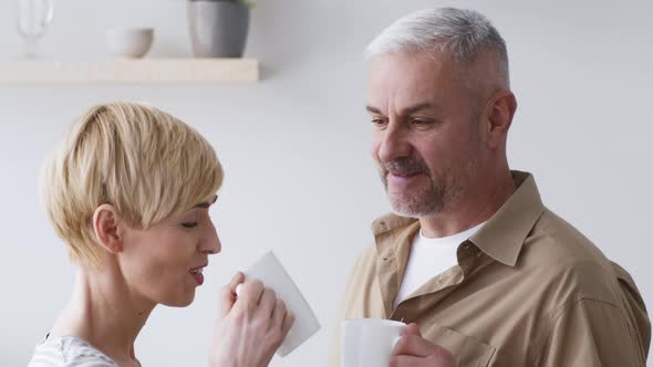 Portrait Of Cheerful MiddleAged Couple Enjoying Coffee In Kitchen