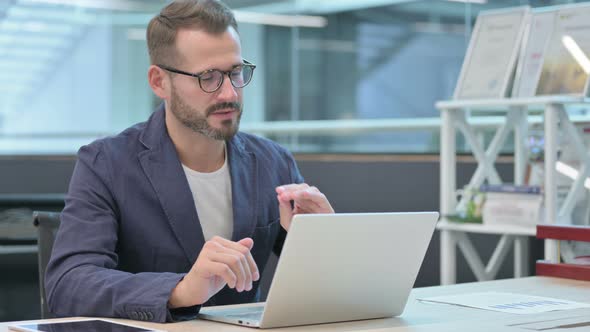 Middle Aged Businessman Talking on Video Call on Laptop in Office