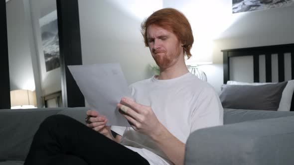 Redhead Man Upset after Reading Documents, Feeling Sad