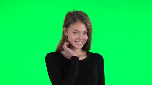 Young Woman Coquettishly Smiling While Looking at Camera and Winks. Green Screen
