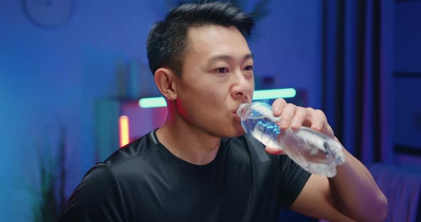 Asian Guy in Sportswear which Drinking Water During Exercising on Running Track