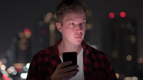 Young Handsome Hipster Man Talking On The Phone Against View Of The City At Night