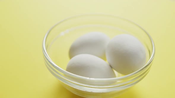 Video of close up of biracial man putting egg into bowl on yellow background