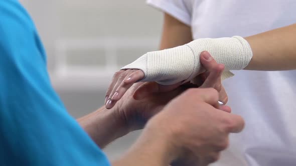 Traumatologist Putting Wrist Elastic Wrap to Female Patient, Arthritis Problem