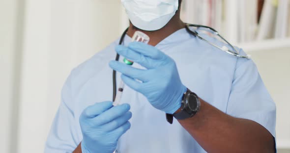 Video of african american male doctor in face mask preparing vaccine