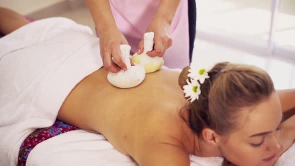 Massage Therapist Using Herbal Compress on Woman