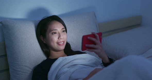 Woman use of mobile phone and lying on bed