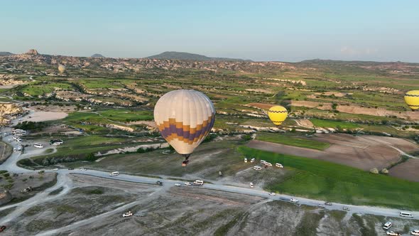 Hot air balloons fly over the mountainous landscape of Cappadocia, Turkey.