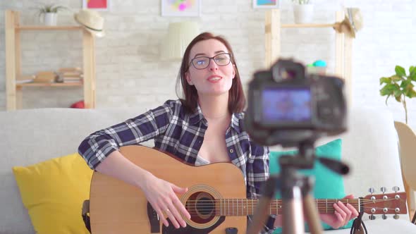 Portrait Young Woman Blogger Sitting on the Couch with a Guitar in His Hands in Front of the Camera