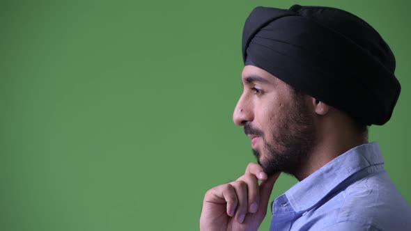 Profile View of Young Handsome Bearded Indian Businessman Wearing Turban and Thinking