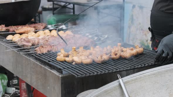 Shish Kebab and Mushrooms on Skewers Cooked on Barbecue at Street Food Festival