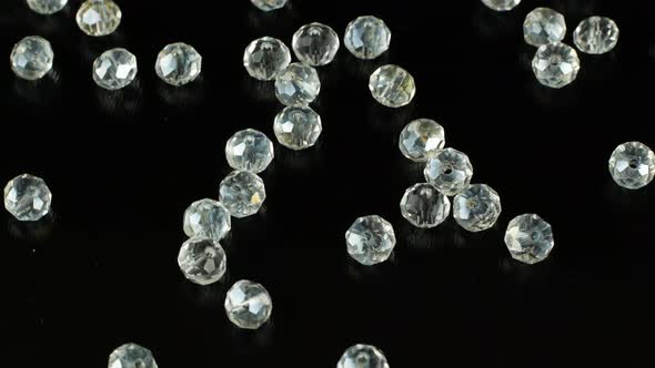 White beads for making jewelry on a black surface and rotating. Iridescent stones for jewelry.