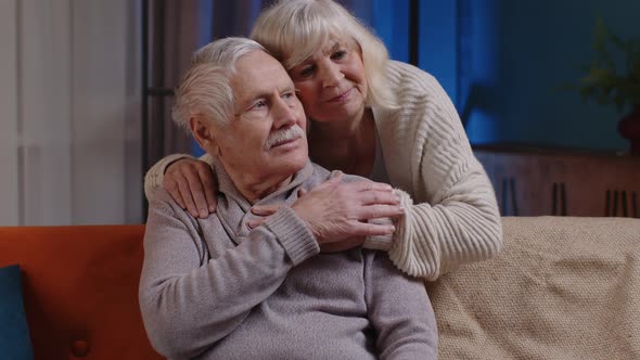 Happy Old Senior Elderly Family Couple Hugging Smiling Smiling Looking at Camera at Home Sofa