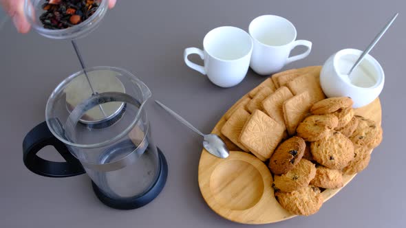 Large-leaf black tea is poured into a transparent glass teapot. Tea jar in hand. Method of brewing