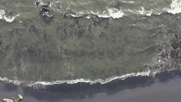 Aerial View Powerful Ocean Waves at Black Volcanic Beach Crashing and Foaming.