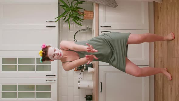 Young Caucasian Woman Fooling Around at Home in the Kitchen Singing and Dancing to the Music