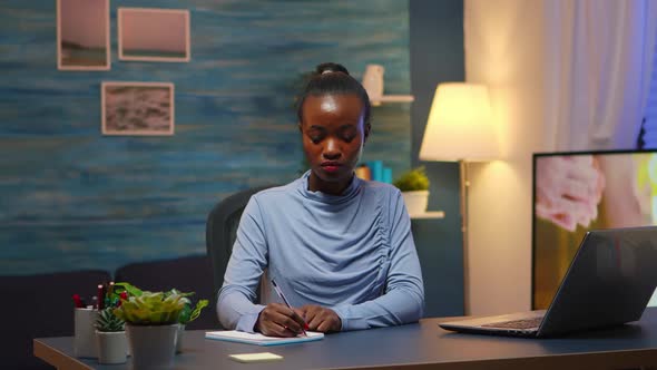 Black Business Woman Writing in Notebook Working Overtime