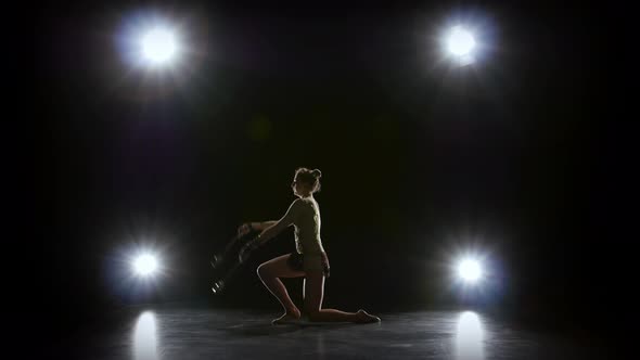 Girl Gymnast with Mace in Hand Revolve Around Him. Black Background. Light Rear