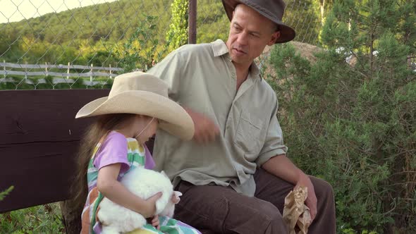 A Farming Family a Father and a Little Daughter with a Rabbit are Sitting Together on the Farm