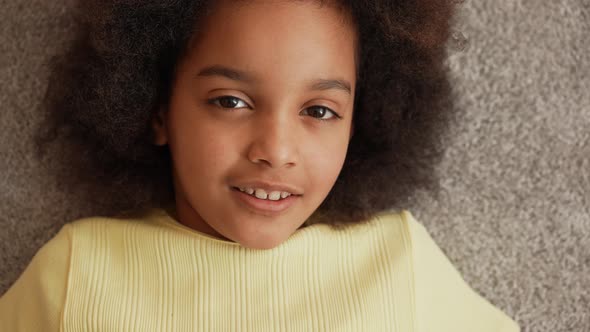 Camera Zooms in on Face and Eyes of Small African American Girl Looking at Camera and Smiling