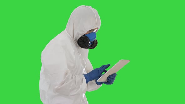 Scientist or Docrot Wearing Biohazard Suits and Protective Masks Using Digital Tablet While Walking