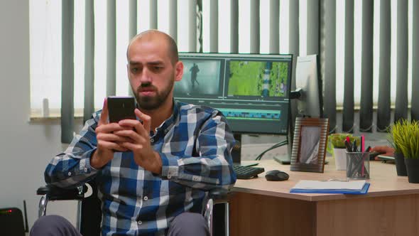 Video Editor in Wheelchair Texting on Smartphone