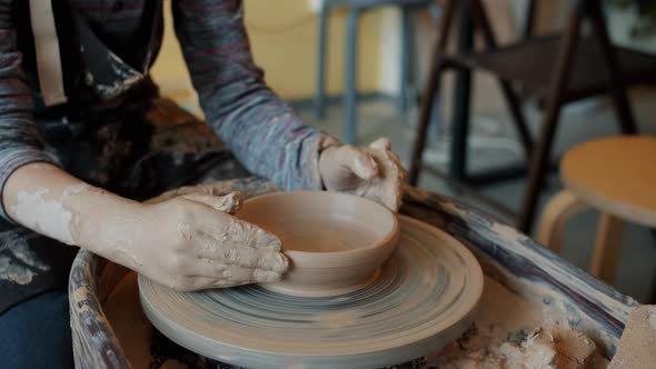 Slow Motion Close-up of Child's Dirty Hands Shaping Bowl From Clay on Pottery Wheel