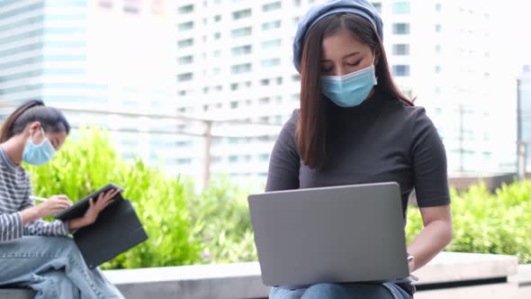 Young asian woman wearing protective face mask while working remotely on computer lapto