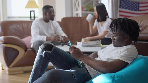 Side View Portrait of Young Confident Freelancer Checking Email on Tablet with Blurred African