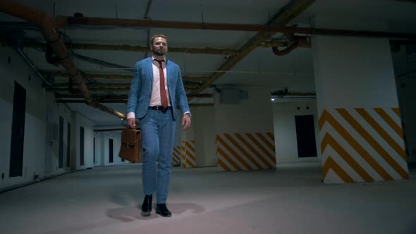 Successful businessman in a classic suit purposefully walks through an underground parking