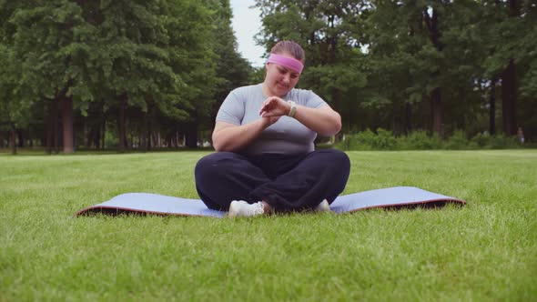 Overweight Woman Practicing Yoga Outdoors Meditating Sitting on Fitness Mat in Nature