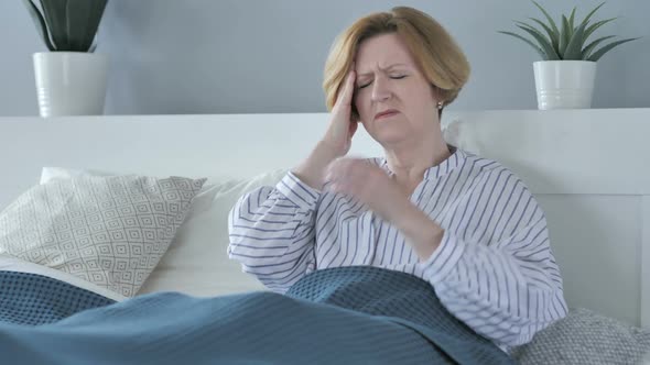 Upset Old Senior Woman with Headache While Sitting in Bed