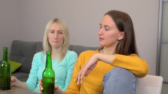 Two girls, drinking beer and eating delicious pizza, at home in their kitchen.