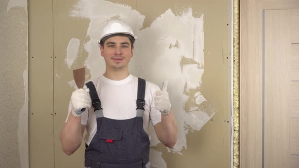 A Builder with a Spatula in His Hand Looks at the Camera and Shows the Class and Smiles