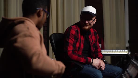 Back View of AfroAmerican Guitarist Singer Playing Guitar and Sing Song to Bearded Sound Producer