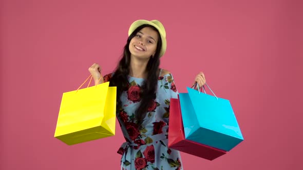 Girl Dancing with Colorful Packages in Their Hands. Pink Background. Slow Motion