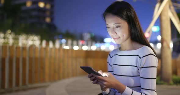 Woman looking at mobile phone in city at night