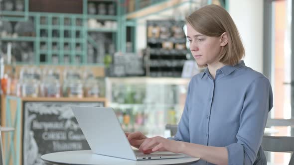 Young Woman Looking at Camera While Working on Laptop