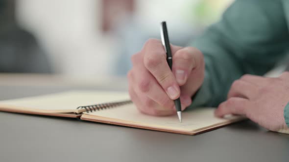 Close Up of Hands of Man Writing in Notebook