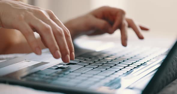 Female Hands Typing on Laptop Keyboard on Bed at Bedroom Close Up View