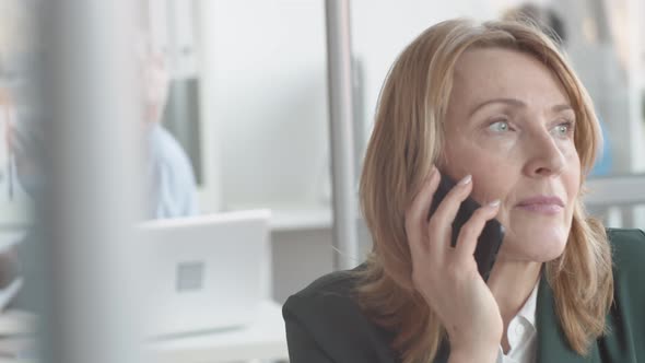 Smiling Caucasian Lady Talking on Smartphone in Office