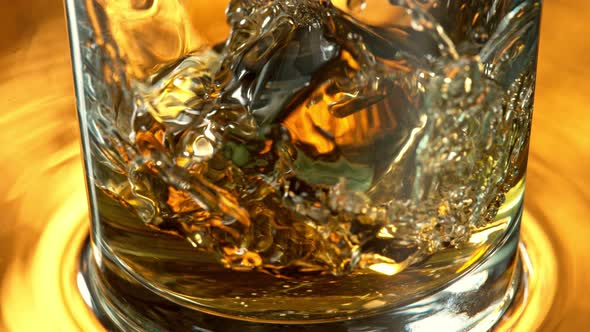 Super Slow Motion Detail Shot of Ice Cube Falling Into Whiskey at 1000 Fps