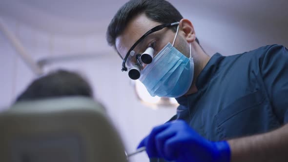 Portrait of Professional Concentrated Middle Eastern Dentist in Binocular Loupes and Face Mask