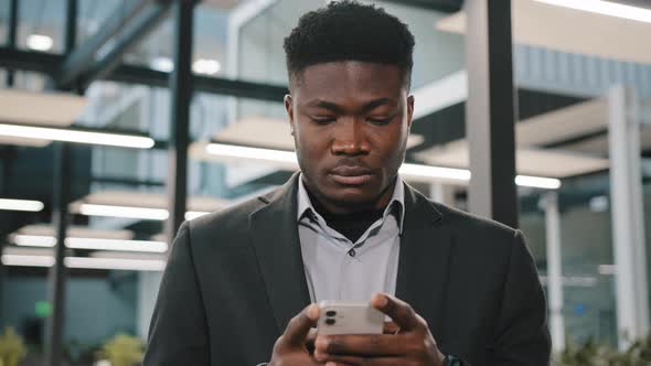 Serious Young Man African American Office Worker Searching Smartphone Internet Choosing Making Order