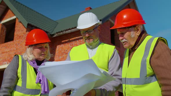 Realestate Agent Selling New House to Senior Grandmother Grandfather Showing Building Blueprints