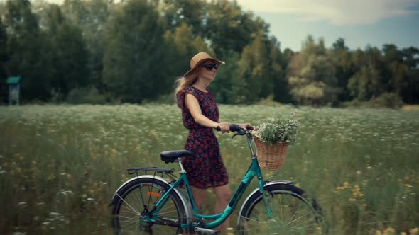 Girl In Sunglasses And Dress.ourist Girl Relaxing On Countryside Wildflower Field.Woman Cyclist.