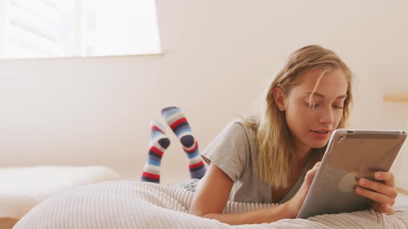 Woman using digital tablet while laying on a bean bag indoors