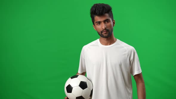 Portrait of Confident Positive Middle Eastern Footballer Posing on Green Screen with Soccer Ball